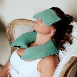Woman relaxing on a chair using Peachskin Neck Wrap Pillow in Salt Lake City, UT | Santosh Yoga Institute