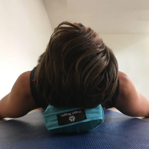 Man lying on Pranayama yoga- bolster aqua in Salt Lake City, UT | Santosh Yoga Institute