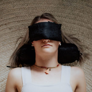 Lying Woman Using Silk Neck Pillow and Eye Pillow with Herbal Filling in Salt Lake City, UT | Santosh Yoga Institute