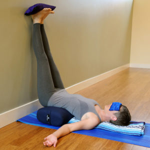 Young man doing yoga using standard yoga bolster pillow in Salt Lake City, UT | Santosh Yoga Institute
