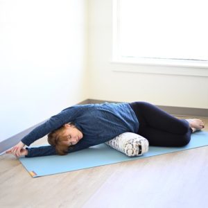 Woman doing yoga with junior yoga bolster in Salt Lake City, UT | Santosh Yoga Institute