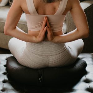 Woman doing exercise while sitting on v-shaped-meditation cushion black in Salt Lake City, UT | Santosh Yoga Institute